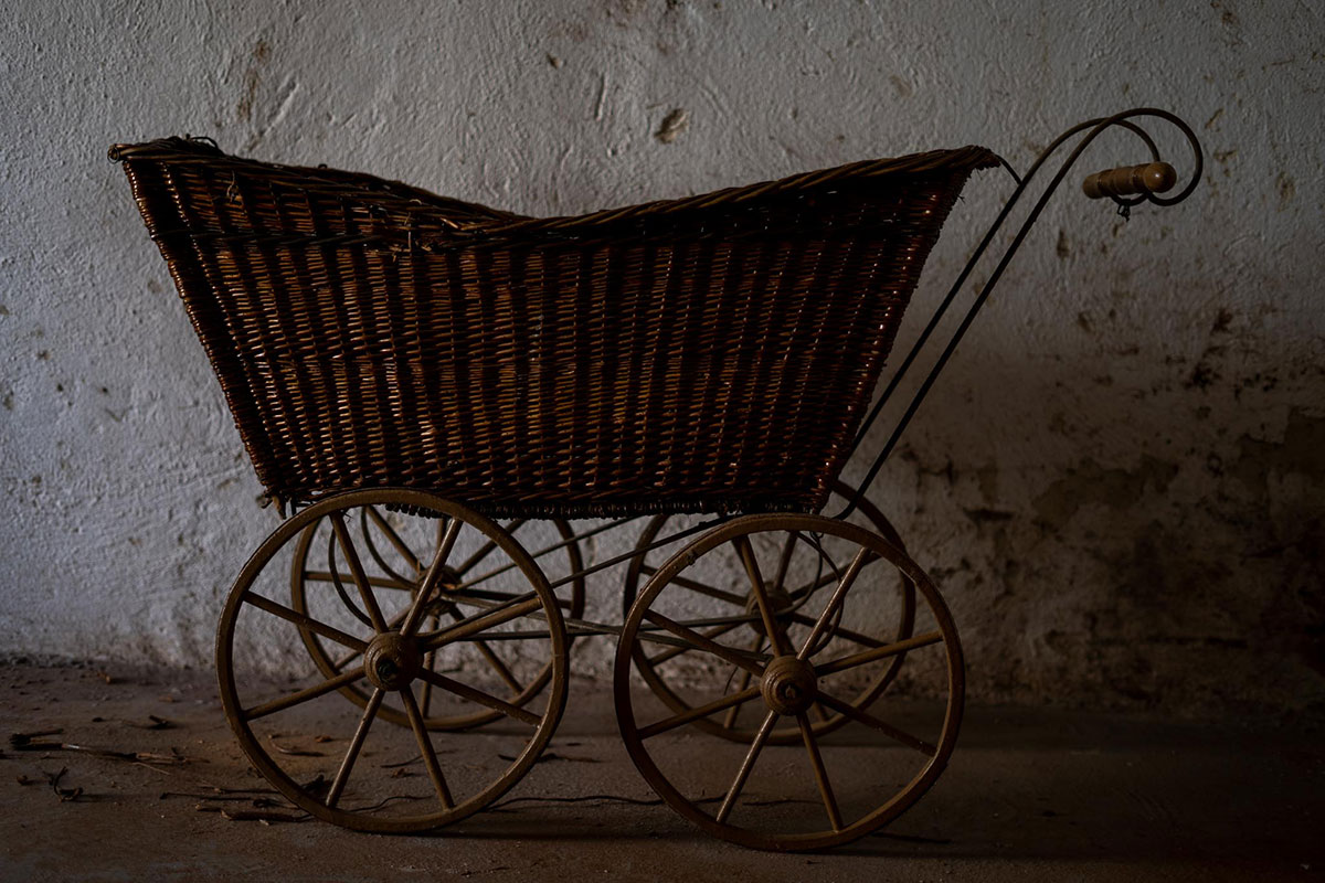 Kinderwagen aus Holzrädern und einem Korb